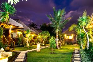a resort at night with palm trees and lights at Koji Garden Huts - CHSE Certified in Nusa Lembongan