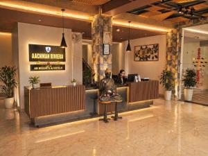 a lobby of a restaurant with a man sitting at a counter at Aachman Riviera Valley dharamshala by NAINA STAYCATION in Dharmsāla
