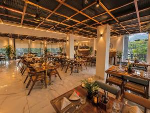 a restaurant with wooden tables and chairs and windows at Aachman Riviera Valley dharamshala by NAINA STAYCATION in Dharmsāla