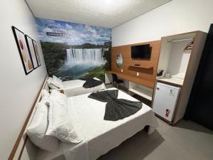 two beds in a room with a waterfall mural on the wall at Alphaville Hotel in Barra do Bugres