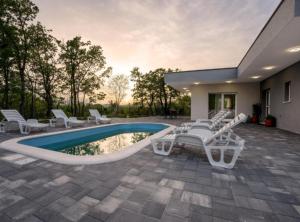 a patio with white chairs and a swimming pool at Villa Peace Oasis in Lovreć