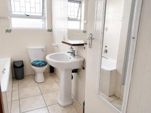 a white bathroom with a toilet and a sink at The Deck in Jeffreys Bay +17 photos