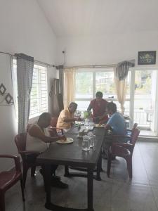 a group of people sitting at a table eating at Prithivee Homestay in Kotagiri