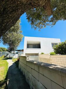 a white house with a brick wall and a tree at Casa Rural Vacacional in Puerto Real