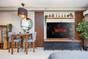 a living room with a television and a table and chairs at Airport Haven Condotel - near Mactan-Cebu Airport 13 mins ride, Self Check-In, Wifi, Netflix, pool and Balcony view in Lapu Lapu City