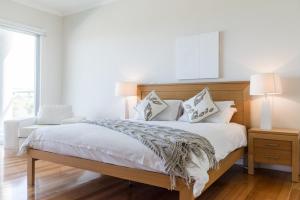 a bedroom with a large bed with white sheets and pillows at The Edge in Robe