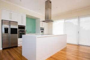 a kitchen with white cabinets and a stainless steel refrigerator at The Edge in Robe