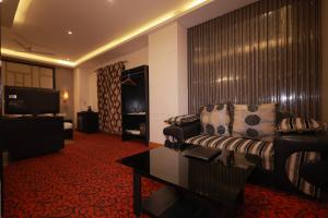 a hotel room with a couch and a television at Hotel Kohinoor Palace, Ludhiana in Ludhiana