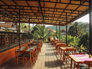 a restaurant with wooden tables and chairs on a balcony at The Garden Sanctuary Homestay in Sidemen