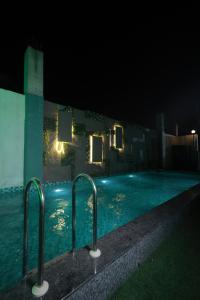 a swimming pool at night with lights in the water at Hotel Kohinoor Palace, Ludhiana in Ludhiana