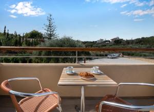 a table and chairs on a balcony with a view of a street at Villaggio Mare Suites in Kalamaki +56 photos