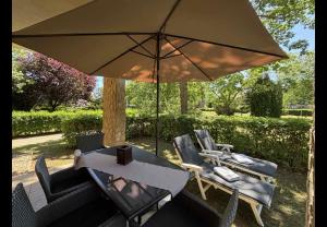 a table and chairs under a large umbrella at Apartman Golf Lux in Bük