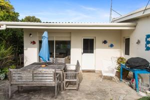 a patio with a table and a blue umbrella at No 5 Red Right on the beach! in Robe