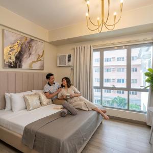 a man and a woman sitting on a bed at 27th Palace at One Manhattan in Bacolod