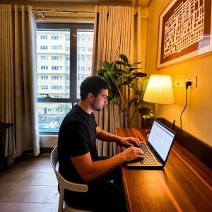 a man sitting at a desk using a laptop computer at 27th Palace at One Manhattan in Bacolod +10 photos