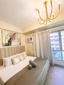 a bedroom with a large bed with a chandelier at 27th Palace at One Manhattan in Bacolod