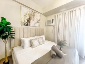 a white bed in a room with a large window at 27th Palace at One Manhattan in Bacolod