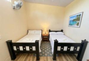 two beds in a room with a lamp and a table at Agujas hostel in Puerto Jiménez