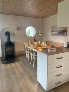 a kitchen with a stove and a table with chairs at Sommerhuset i Saltum in Saltum +4 photos