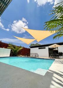 a swimming pool with a yellow umbrella over it at Agujas hostel in Puerto Jiménez