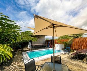 a pool with an umbrella and a table and chairs at Agujas hostel in Puerto Jiménez +12 photos