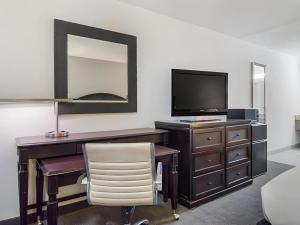 a bedroom with a desk with a television and a chair at Rodeway Inn Lumberton Central in Lumberton