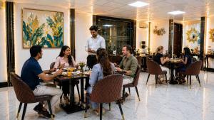 a group of people sitting around a table in a restaurant at Hotel Grand Regency by JMD Group Near Delhi IGI Airport in New Delhi
