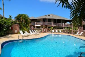 a large swimming pool with chairs and a house at Ka Eo Kai Resort Studio Suite in Princeville
