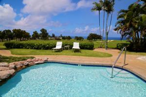 a swimming pool with two chairs and a table at Ka Eo Kai Resort Studio Suite in Princeville