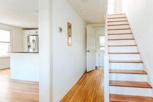 a staircase in a living room with white walls and wooden floors at Green on New in Staunton