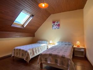 two beds in a attic room with a window at Chez bourdet-pelou in Arette