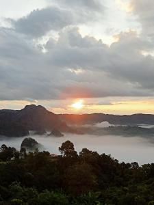 a view of a foggy valley with the sun in the horizon at สบายดีโฮมสเตย์ภูลังกา in Ban Sakoen
