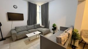 a living room with a couch and a flat screen tv at Banny Homes - Cozy Suite Apartment - Downtown in Abu Dhabi