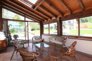 a screened in porch with chairs and tables and windows at Arlotia in Ascarat