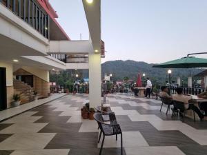 a patio with tables and chairs and people sitting at tables at Hotel Biaspushp Dalhousie in Banikhet