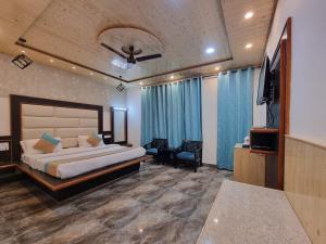 a bedroom with a bed and a flat screen tv at Hotel Biaspushp Dalhousie in Banikhet +8 photos