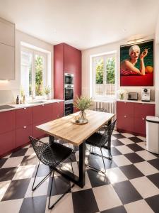 a kitchen with red cabinets and a wooden table and chairs at Villa Avril Gîte Privé Luxe 15 pers- deux piscines intérieure, extérieure-sauna -proche Europapark in Sélestat