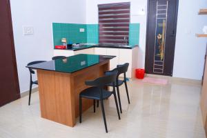 a kitchen with a island with black chairs in it at Thushara Homestay in Kozhikode