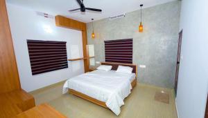 a bedroom with a bed and a ceiling fan at Thushara Homestay in Kozhikode