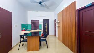 a room with a table and chairs and a kitchen at Thushara Homestay in Kozhikode