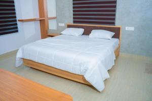 a bedroom with a large bed with white sheets at Thushara Homestay in Kozhikode +2 photos