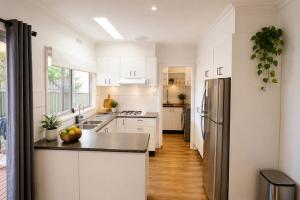 a kitchen with white cabinets and a stainless steel refrigerator at White House Bendigo Garden Retreat in Epsom