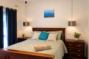 a bedroom with a bed with blue pillows at White House Bendigo Garden Retreat in Epsom
