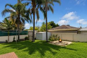 a backyard with palm trees and a fence at White House Bendigo Garden Retreat in Epsom