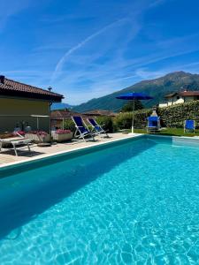a blue swimming pool with chairs and a house at Residence Il Bosso in Domaso