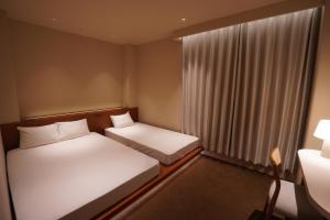 a small room with two beds and a window at TABISAI HOTEL Premium 博多-中洲 in Fukuoka