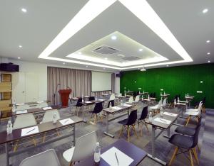 a classroom with tables and chairs and a green wall at Hotel de Art Wonderland in Shah Alam