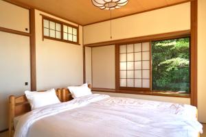 a bedroom with a bed and two windows at 海を望む東伊豆の一棟貸し ula Ocean-view private stay in Izu in Higashiizu