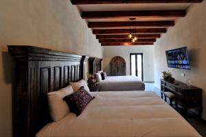 a bedroom with two beds and a dresser in it at Hotel Camino Del Bosque Centro Pádel in Cholula
