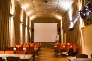 a conference room with tables and chairs and a white screen at Merilän Kartano in Utajärvi